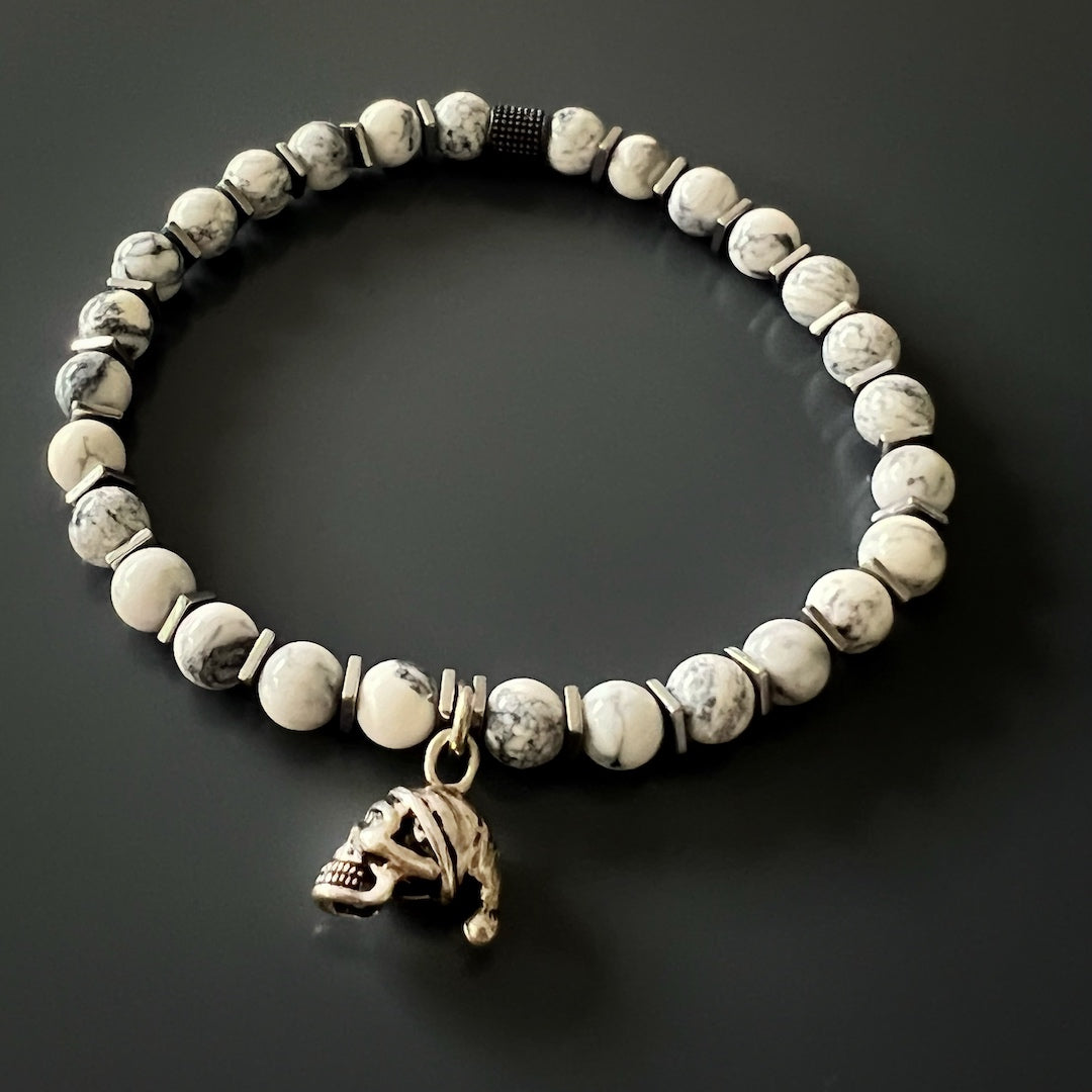 Experience the edgy elegance of the Men&#39;s Spiritual Beaded Skull Bracelet, showcasing a Sterling Silver skull charm and marbled Howlite stone beads.