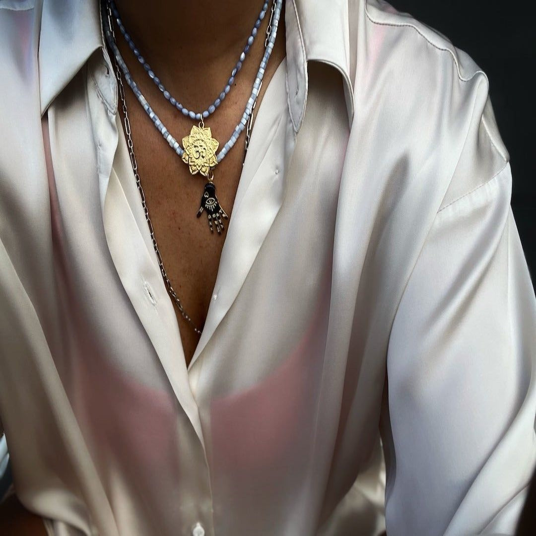 A different angle of the Grounding Necklace, highlighting the intricate details of the hand pendant. The model wearing the necklace demonstrates the versatility and style that the necklace brings to any outfit. 
