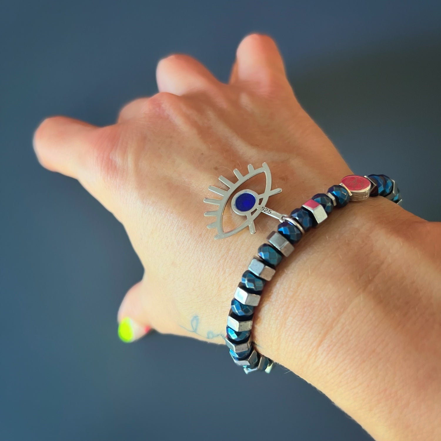 With the Nazar Bracelet adorning the hand model&#39;s wrist, the sterling silver evil eye charm catches the light, creating a captivating shine.