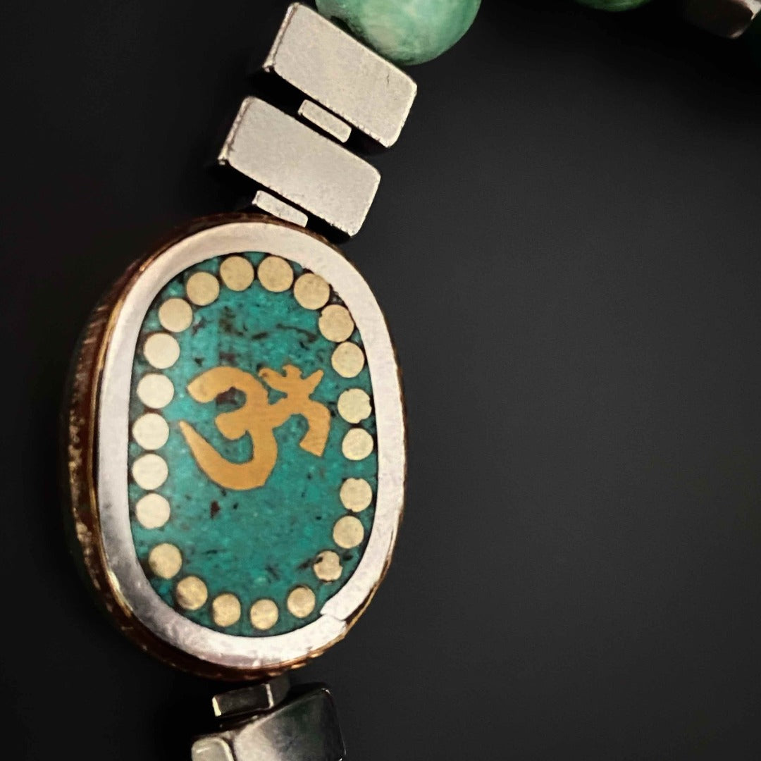 Explore the spiritual significance of the Om Mystic Bracelet, featuring a handmade Ethnic Om Mantra charm bead and green African turquoise stone.