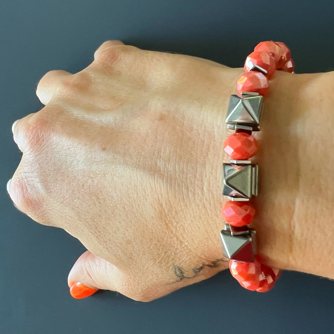 Hand model showcases the beauty and energy of the Orange Energy Bracelet, with its vibrant orange crystal beads and silver hematite stone beads.