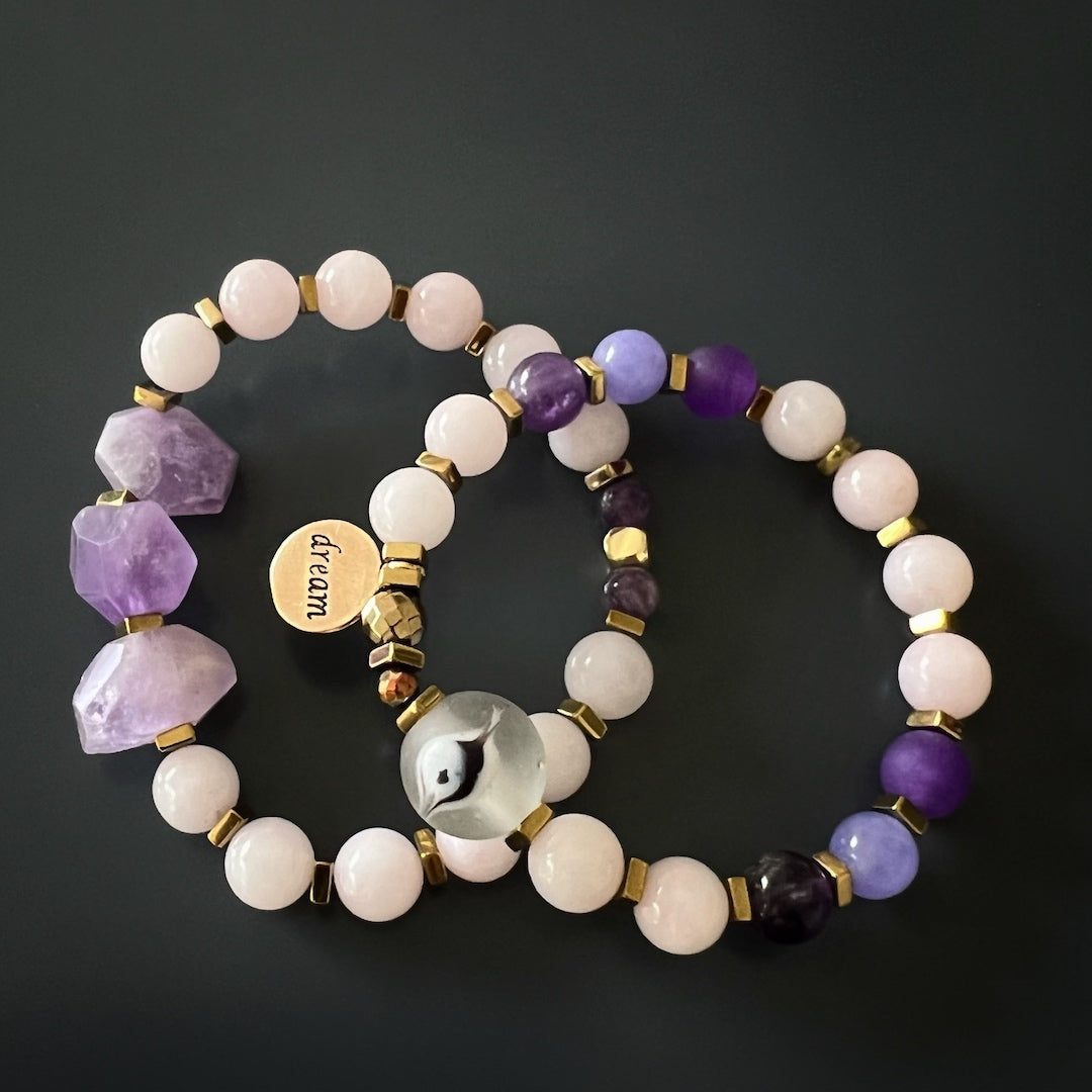 Discover the calming energy of the Peaceful Mind Bracelet Set, showcasing the rose quartz and amethyst beads, a glass evil eye bead, and a bronze Dream mantra charm.