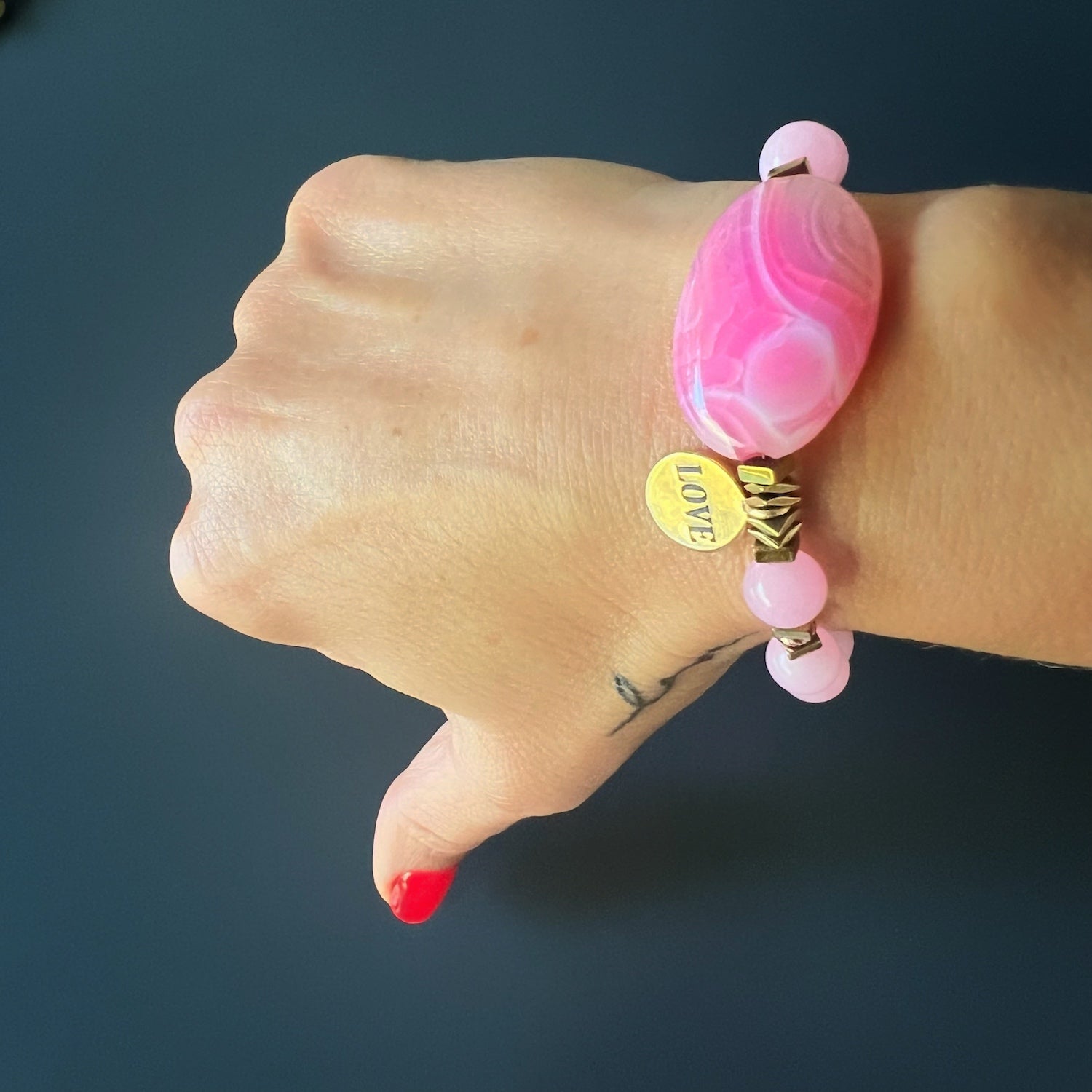 See how the Pink Agate Love Bracelet adorns the hand model's wrist, radiating romance and enchantment.