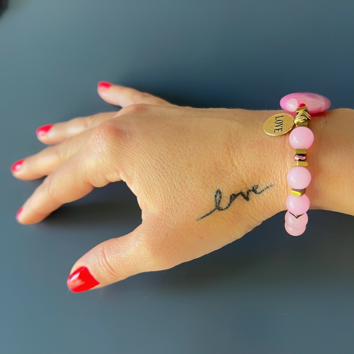 See the Pink Agate Love Bracelet beautifully displayed on the hand model&#39;s wrist, a symbol of love and positive energy.