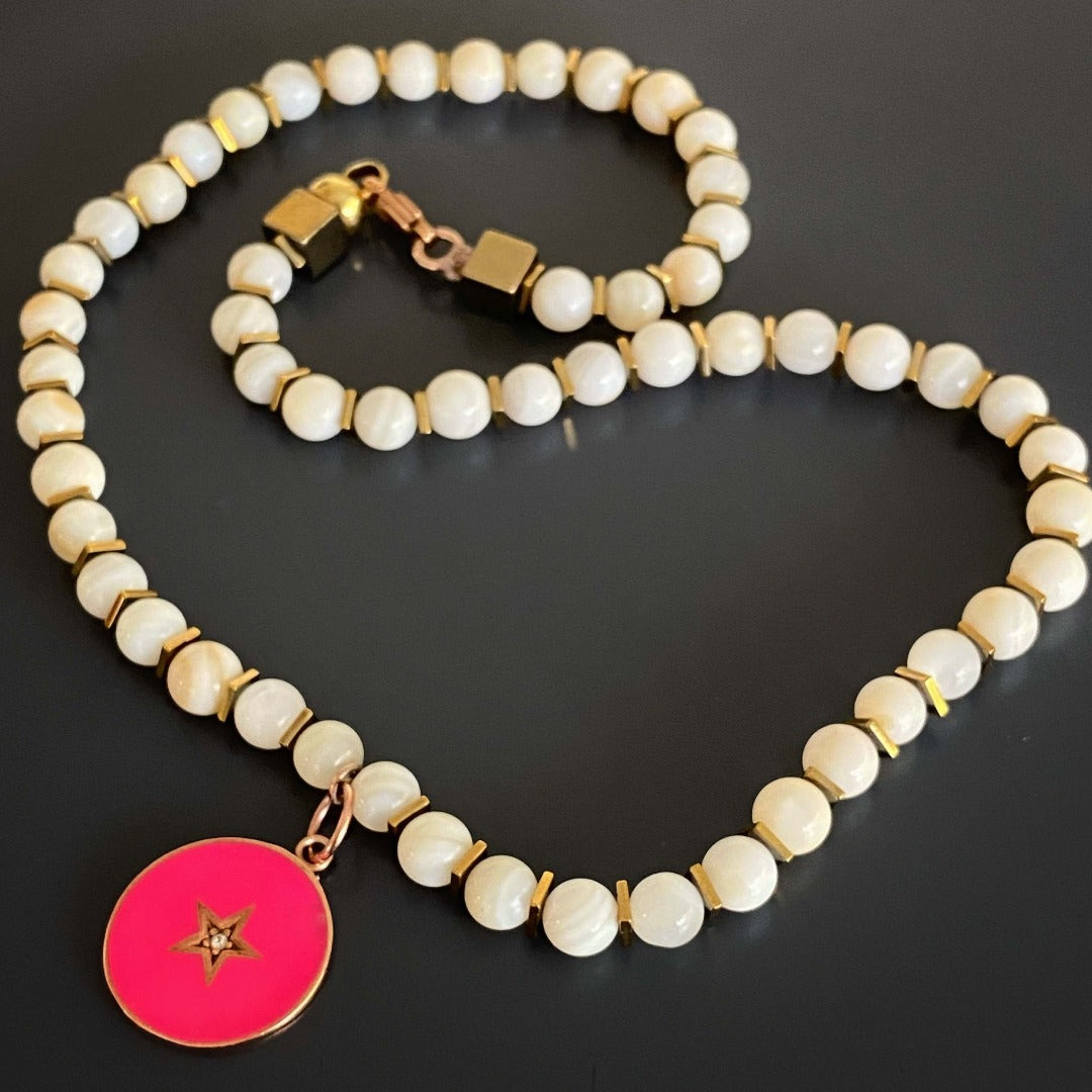 Make a statement with the Pink Star White Choker Necklace, a handmade piece that combines the beauty of tridacna stones with a pink enamel star charm.