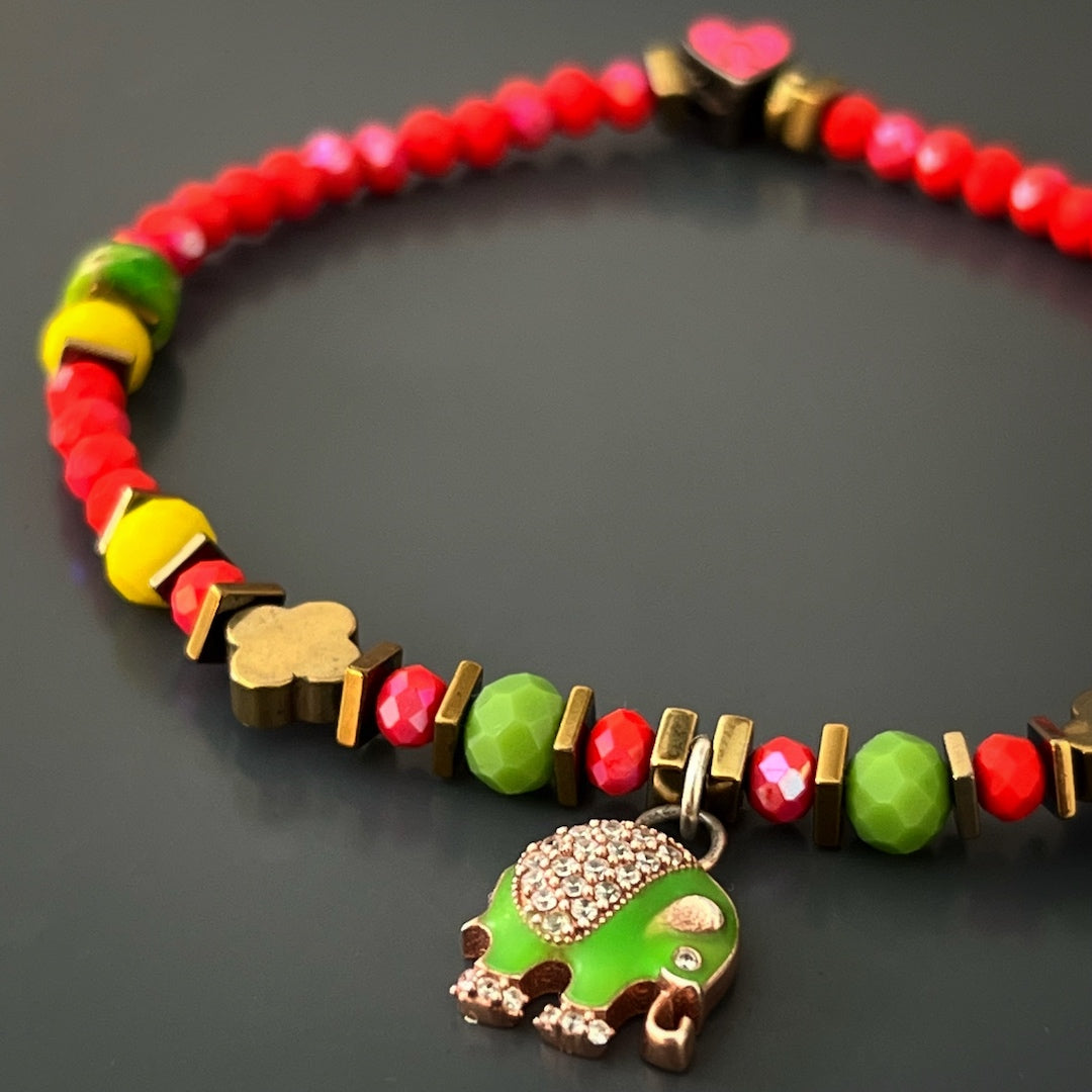 The Powerful Symbol Anklet combines vibrant red crystal beads, calming green jasper beads, a gold color hematite floral bead, and symbolic silver charms, reflecting protection, luck, and positivity.