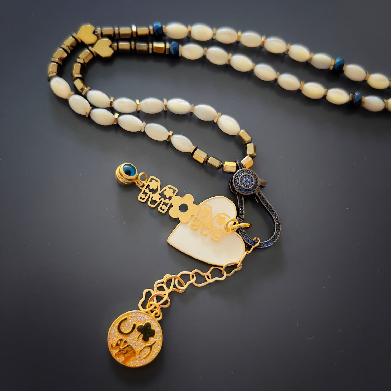 Protective symbols on the Pure Love Mom Necklace, including the evil eye charm and heart-shaped chain links, representing love and protection.