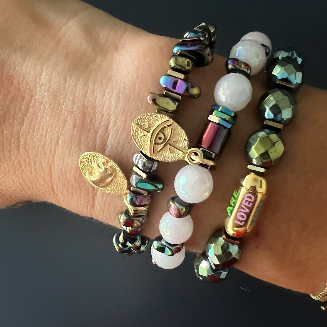 Experience the soothing energy as the hand model wears the Quartz Protection Bracelet, adorned with multicolor hematite stone beads and a stunning Rose Quartz accent.