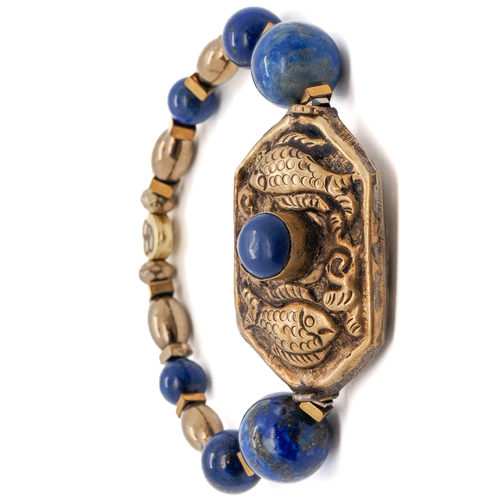 Explore the significance of the Samsara Bracelet, adorned with Lapis Lazuli stone beads and a Nepal handmade Golden Fish charm.