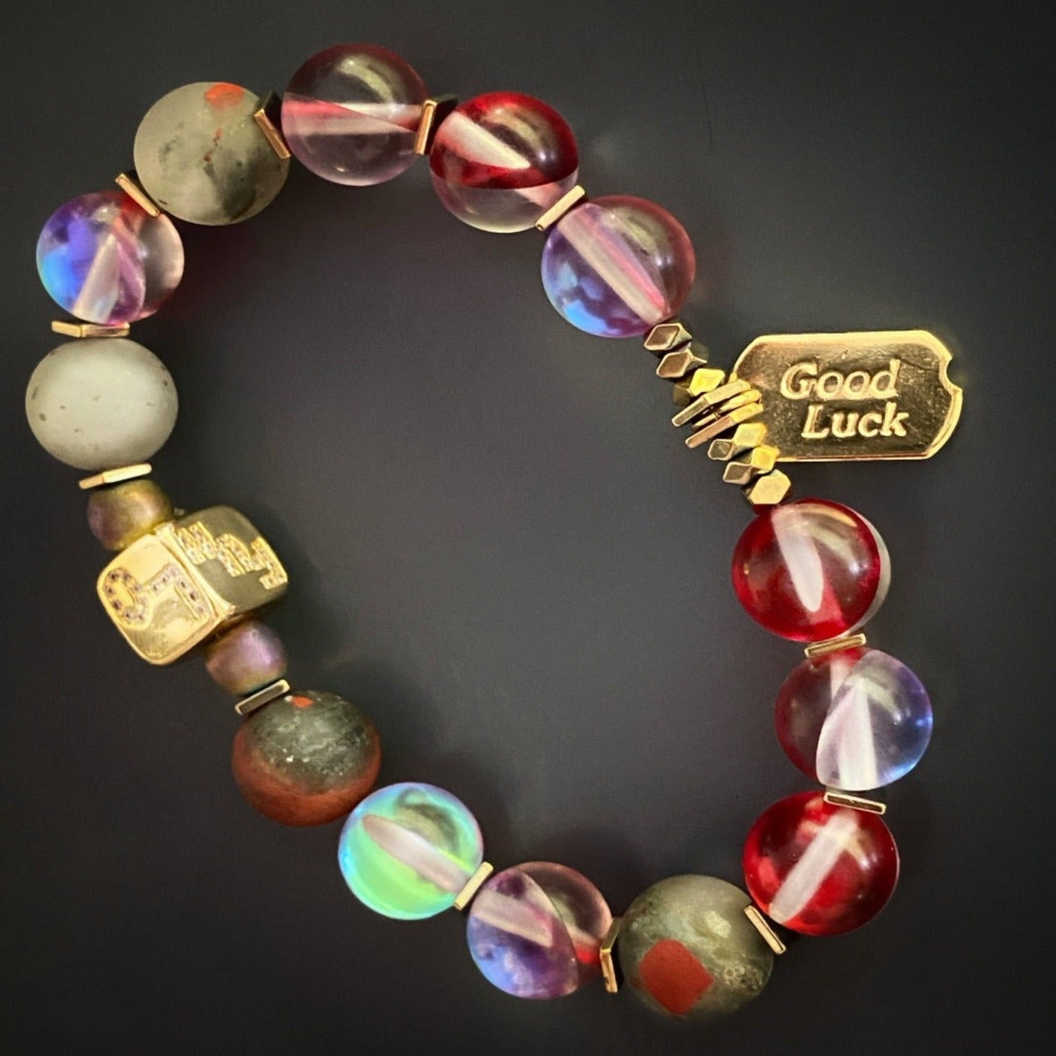 Embrace the positive energy of the Red & Gold Good Luck Bracelet, adorned with red and grey blood stone beads and an 18K gold-plated charm.
