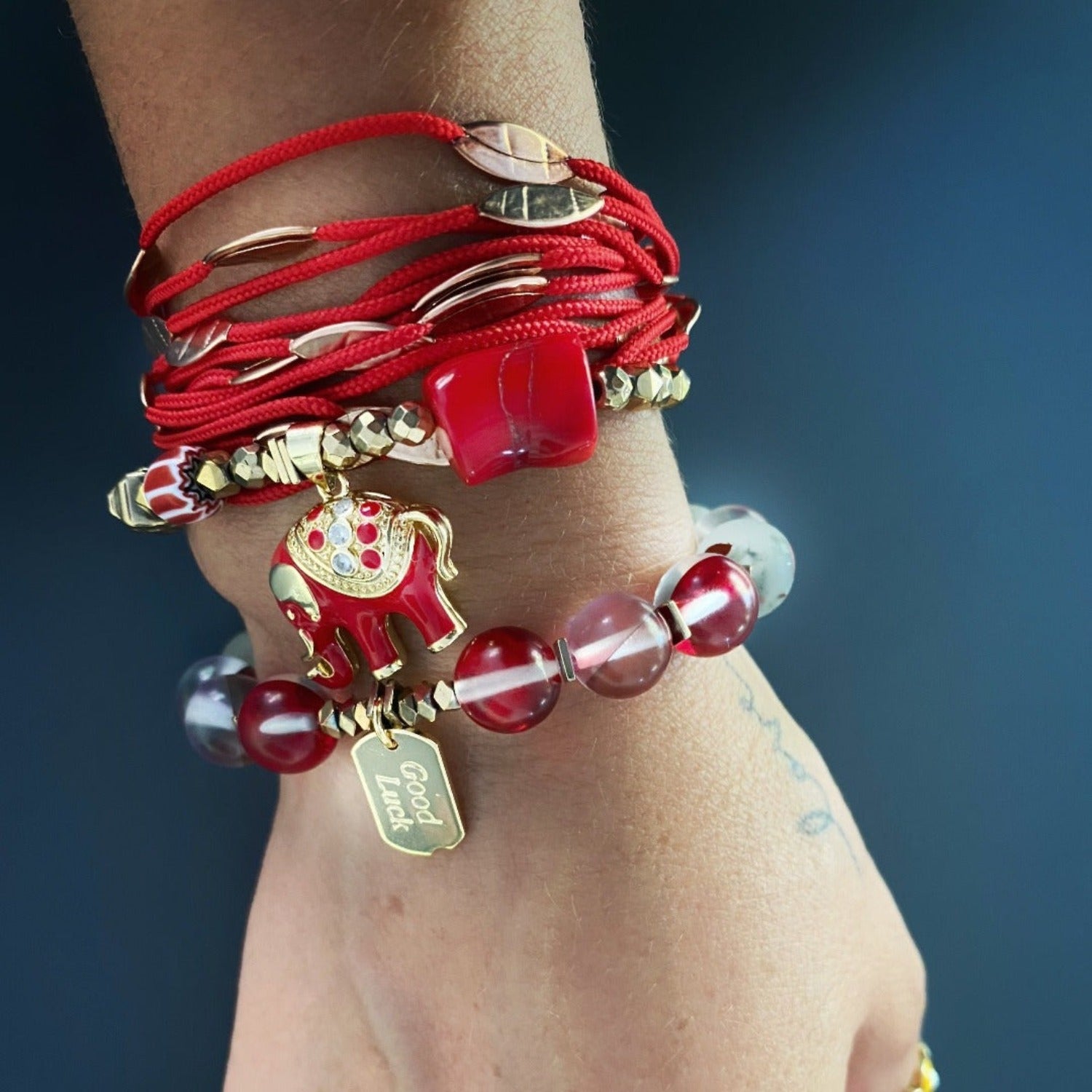 The model showcases the Red & Gold Good Luck Bracelet, radiating positivity and style with its vibrant colors and elegant design.