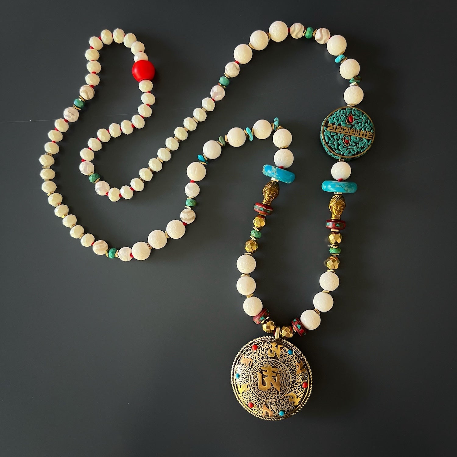 Spiritual Connection: Handmade pendant with turquoise and coral on the Buddha Mantra Necklace.