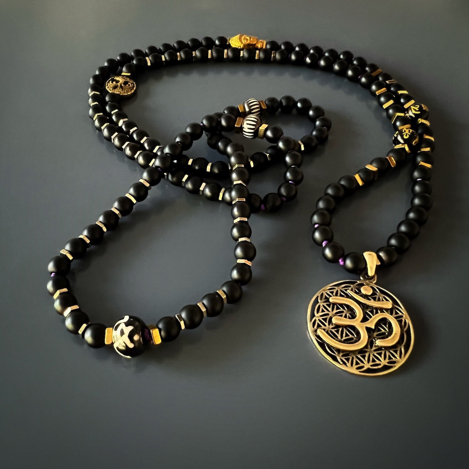 The intricate bronze Om pendant at the center of the Spiritual Yoga Mala Onyx Necklace