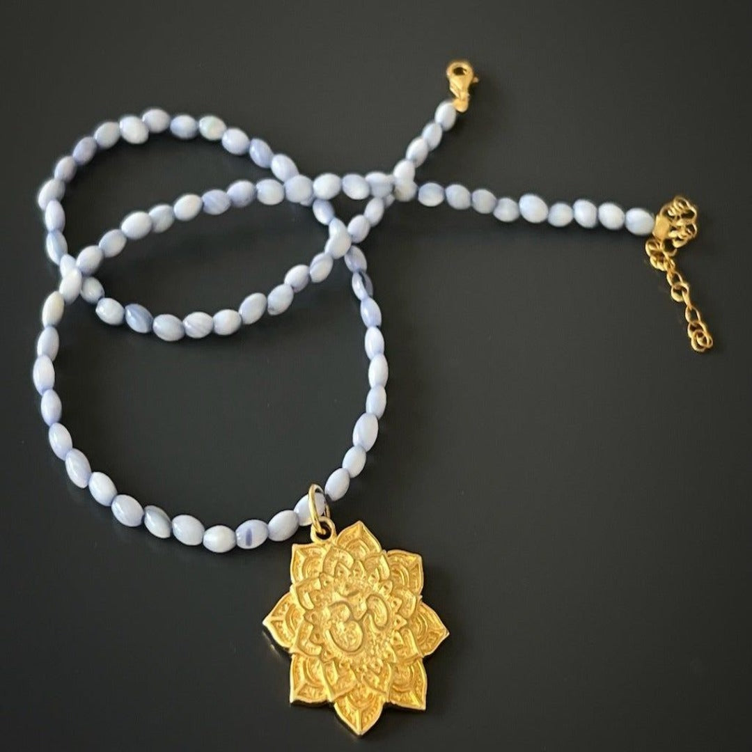 Necklace adorned with blue mother of pearl beads and a symbolic lotus pendant.
