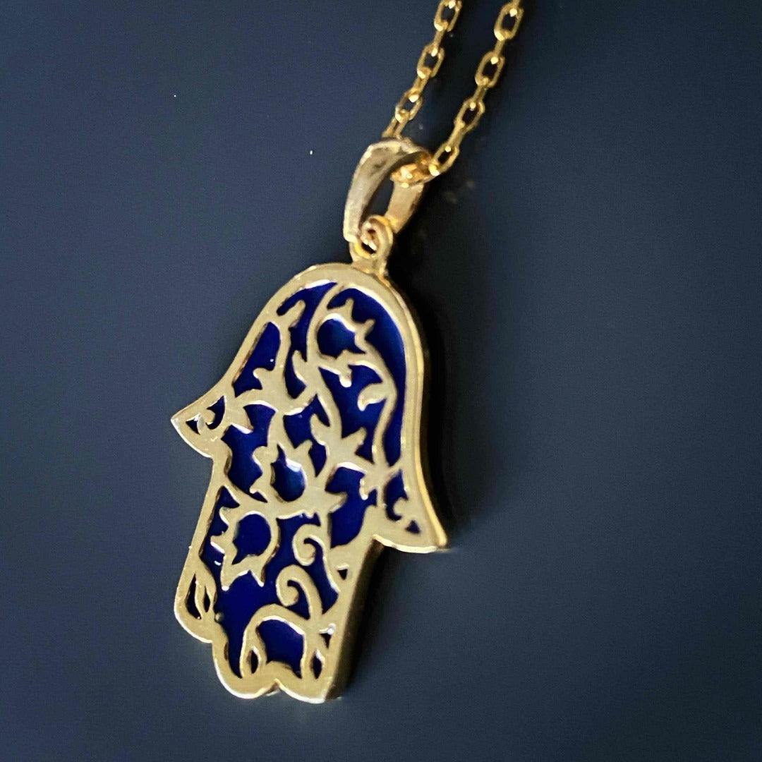 The Stay Positive Hamsa Necklace is a meaningful and stylish accessory, with its vibrant hamsa pendant made of sterling silver and 18K gold plating with enamel accents, reminding you to stay positive.