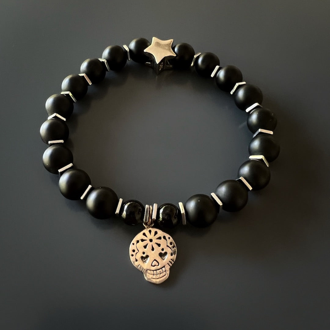 Experience the grounding and protective properties of the Sugar Skull Onyx Bracelet, crafted with beautiful Matte black onyx stone beads and Sterling silver charms.