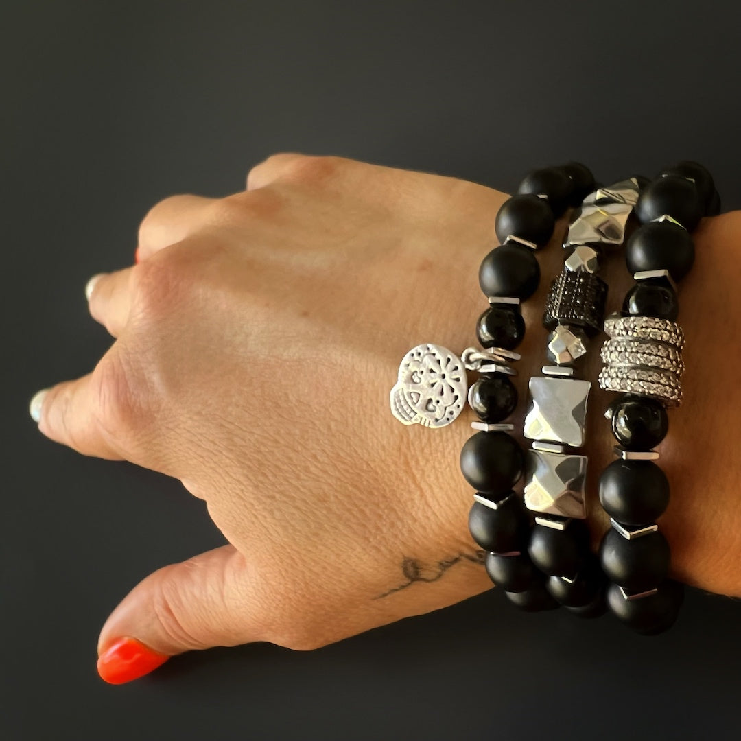 The hand model beautifully showcases the Sugar Skull Onyx Bracelet, featuring the striking sugar skull charm and Matte black onyx stone beads.