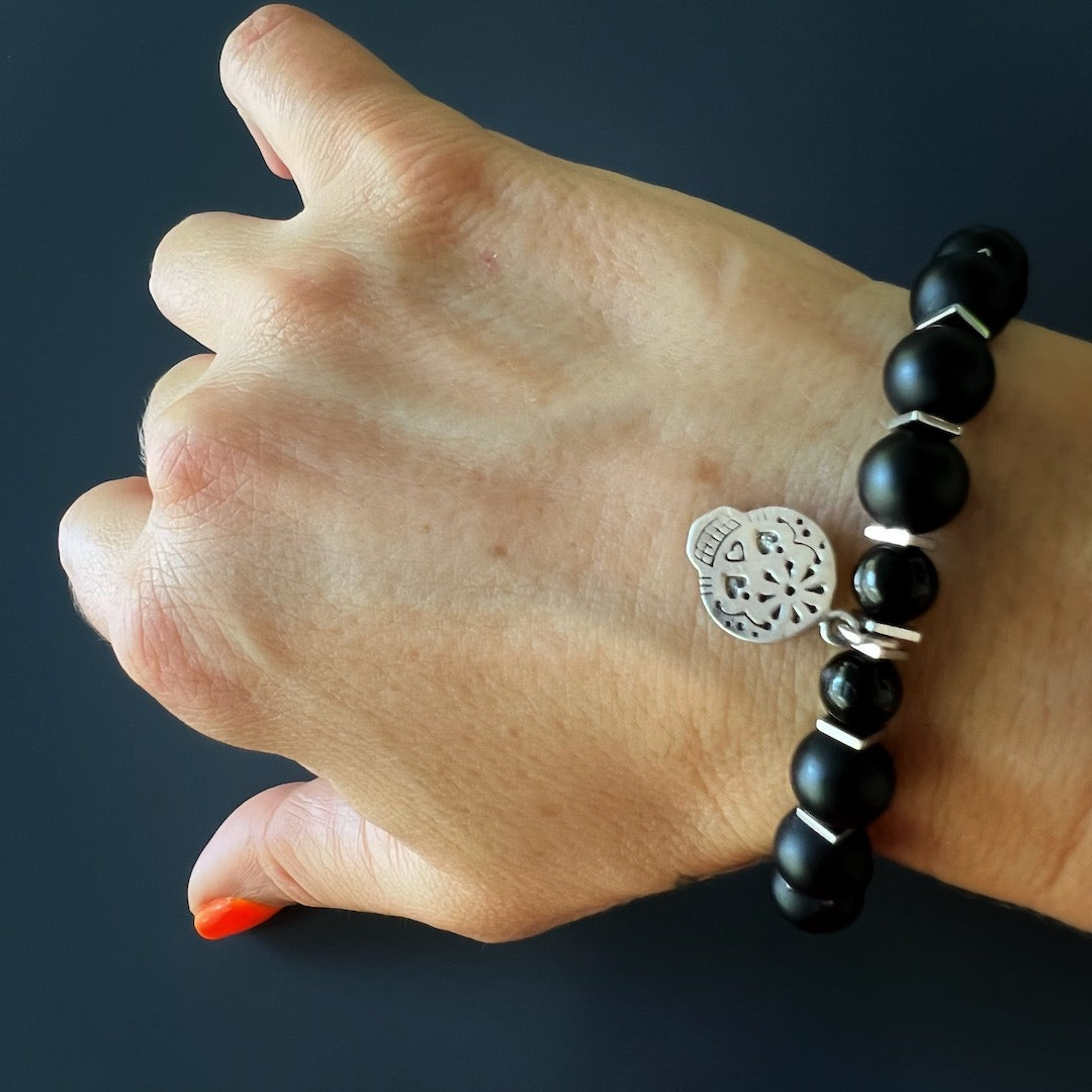 The hand model wears the Sugar Skull Onyx Bracelet, showcasing its bold design and empowering energy.