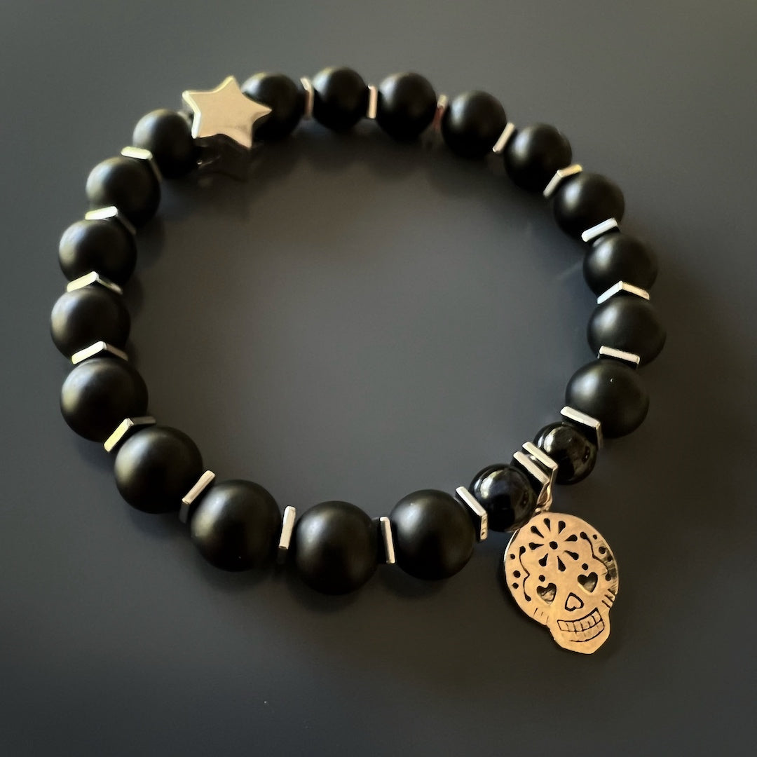 The Sugar Skull Onyx Bracelet combines edginess and elegance, with its Matte black onyx stone beads, Hematite spacers, and Sterling silver charms.