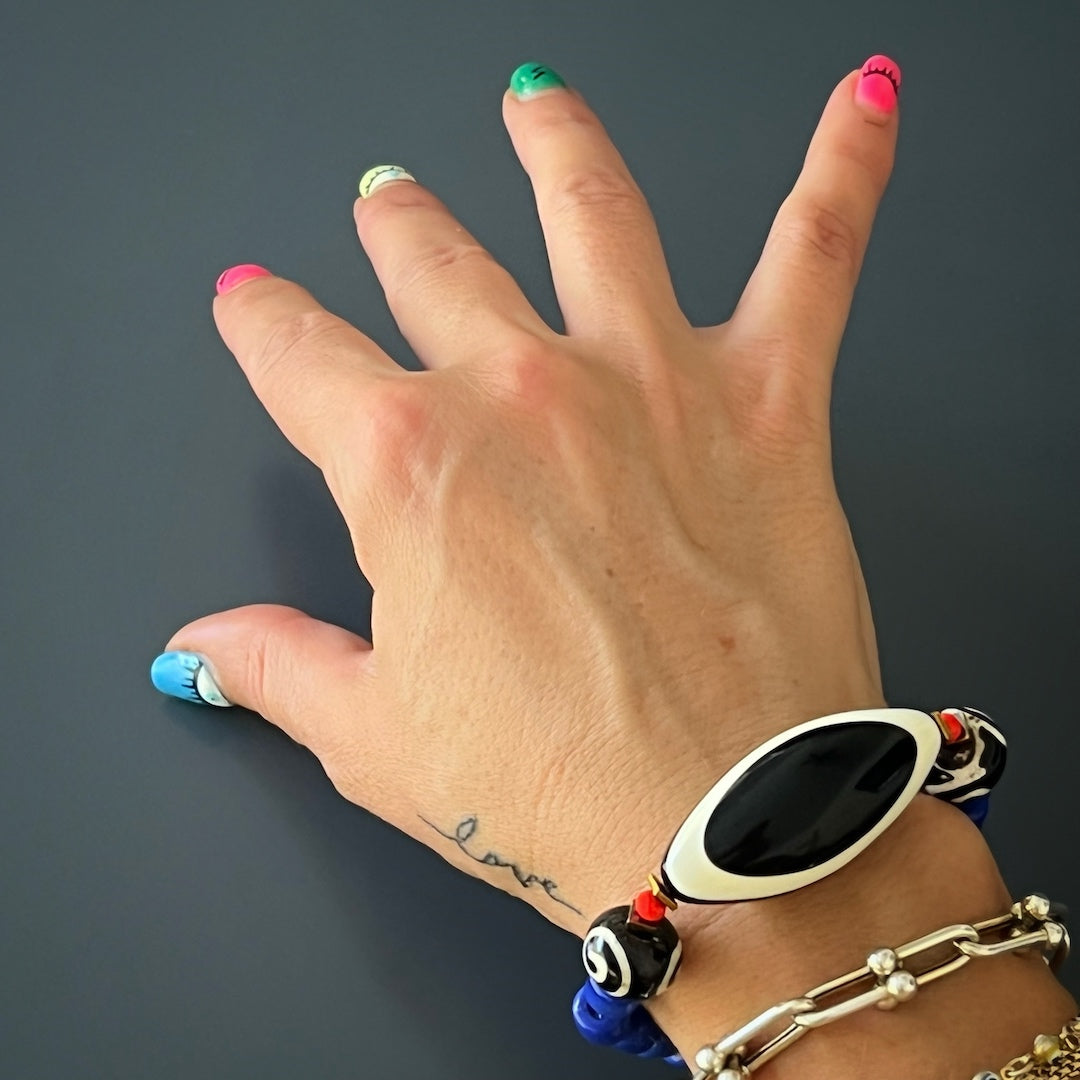 The hand model showcases the Third Eye Tibetan Bracelet, highlighting its unique design and vibrant colors.