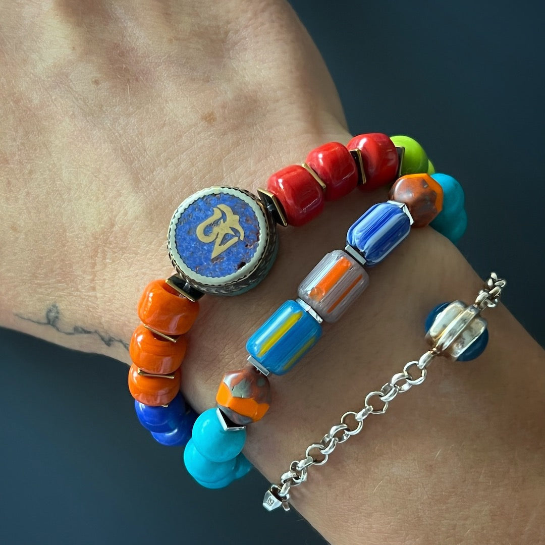 The hand model exudes tropical vibes while wearing the Tropical Vibes Evil Eye Bracelet, adorned with vibrant turquoise stone beads, colorful African beads, and a silver evil eye bead.
