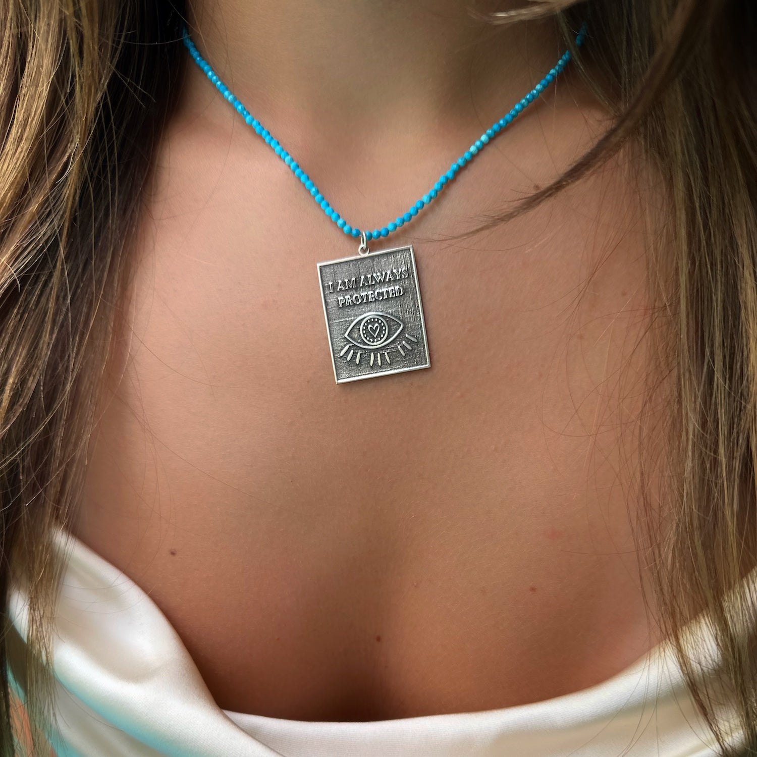 A model confidently wearing the Turquoise 'I Am Always Protected' Necklace, embodying inner strength