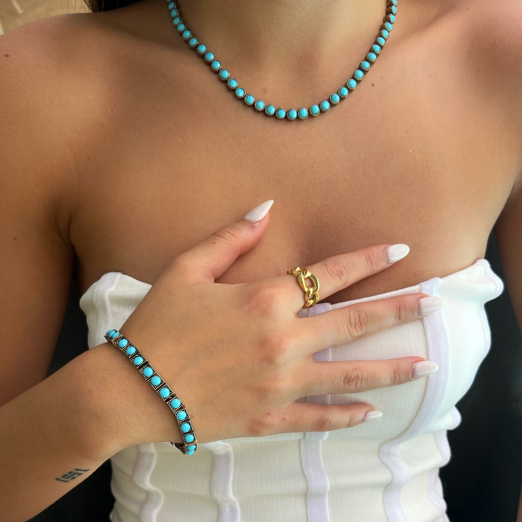 With grace and poise, the model adds a touch of spirituality to their look by wearing the handmade turquoise tennis necklace.