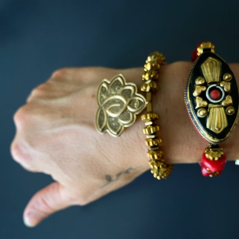 See how the Vintage Style Ethnic Om Bracelet adds a touch of bohemian elegance to the hand model&#39;s style, with its red coral beads and Nepal-inspired charm.