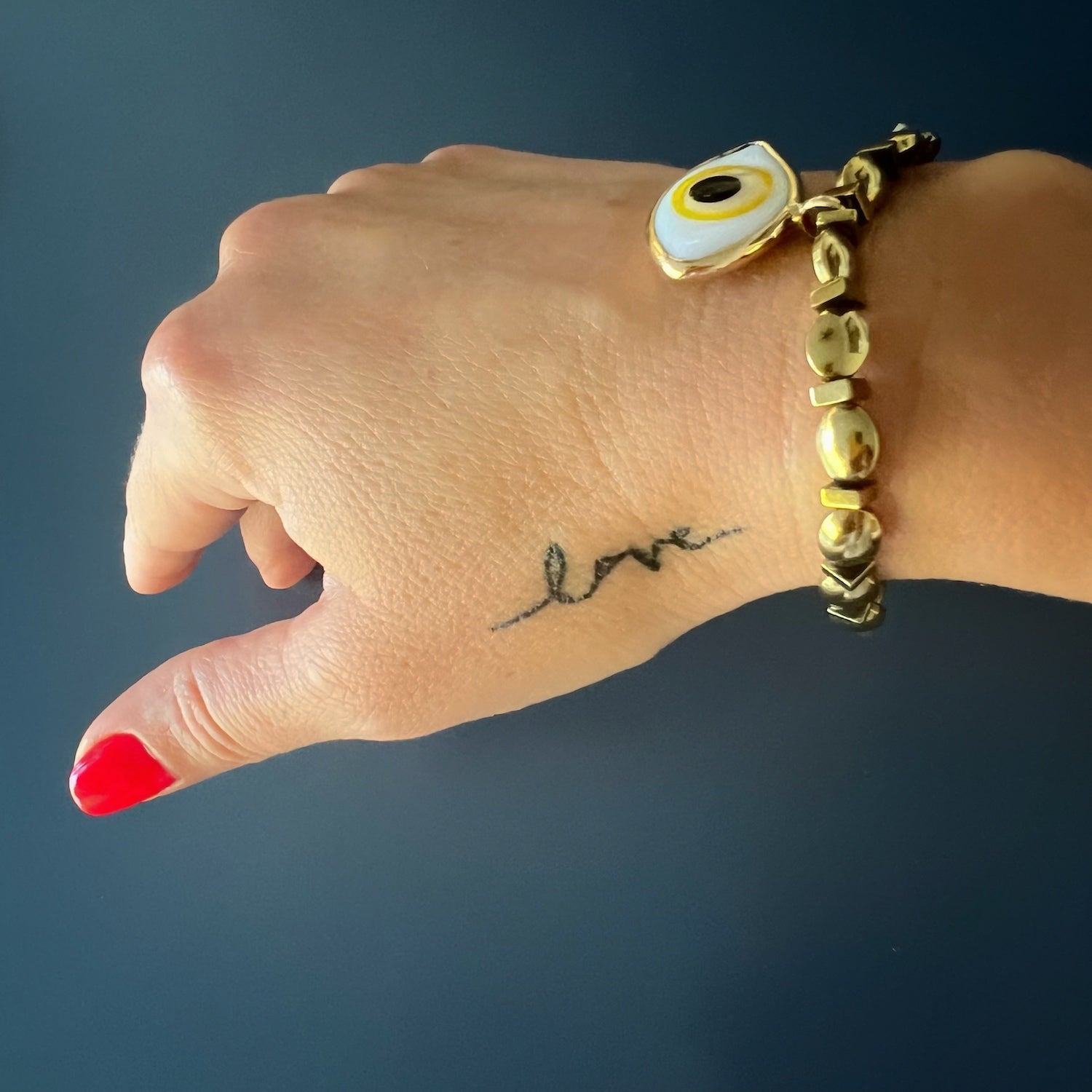 See how the Yellow Evil Eye Bracelet gracefully adorns the hand model&#39;s wrist, capturing attention with its stunning design and symbolism.
