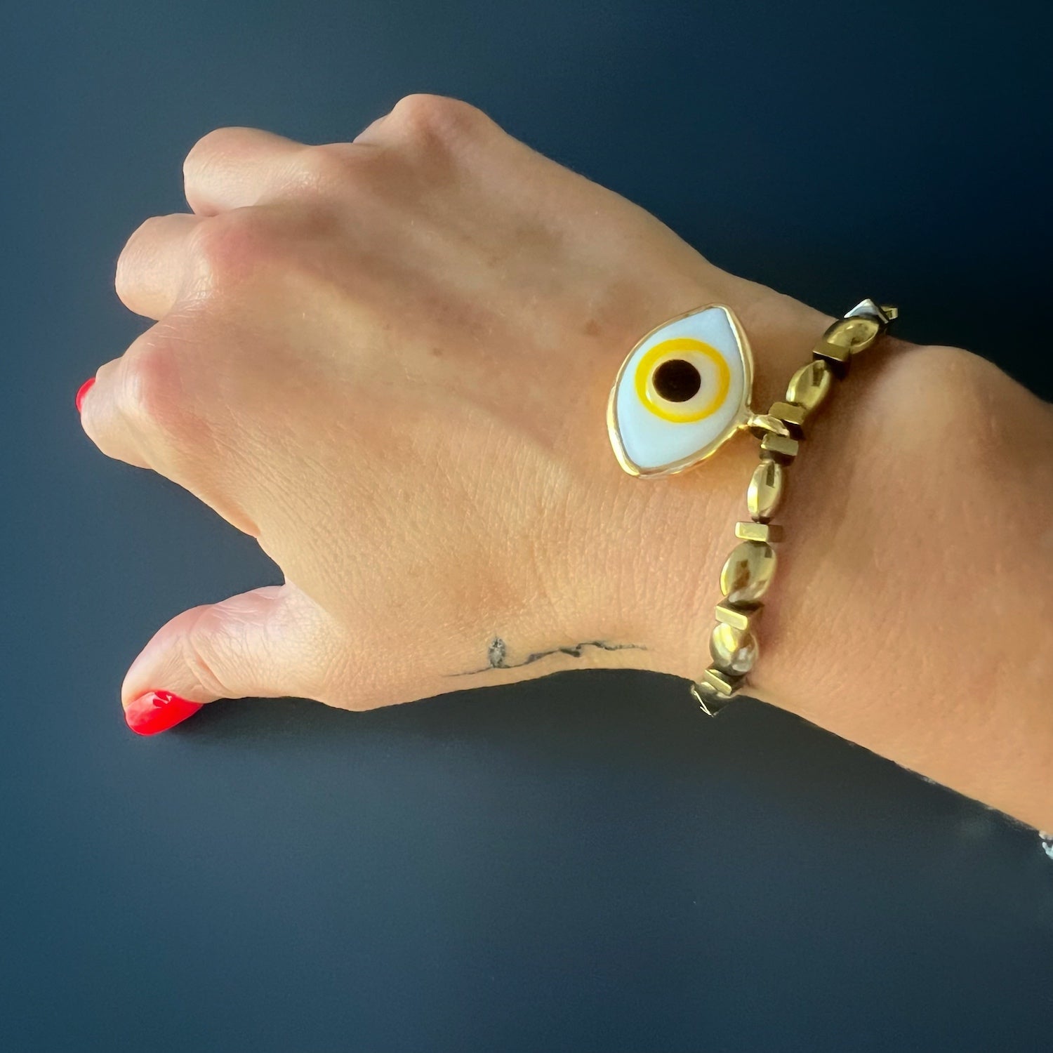 The hand model showcases the Yellow Evil Eye Bracelet, radiating elegance and protection with each movement.