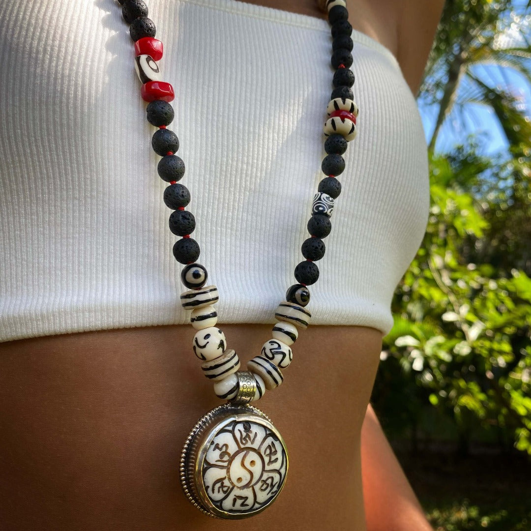 The necklace adds a touch of spiritual elegance to the model&#39;s outfit, symbolizing balance and unity.