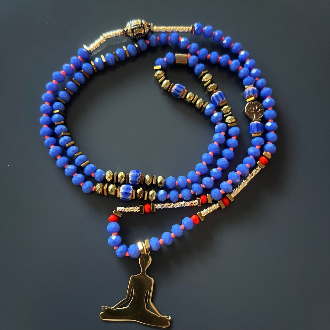 Necklace adorned with blue crystal beads, gold hematite spacers, and a Nepal Om Mani Padme Hum mantra bead, promoting relaxation and focus.