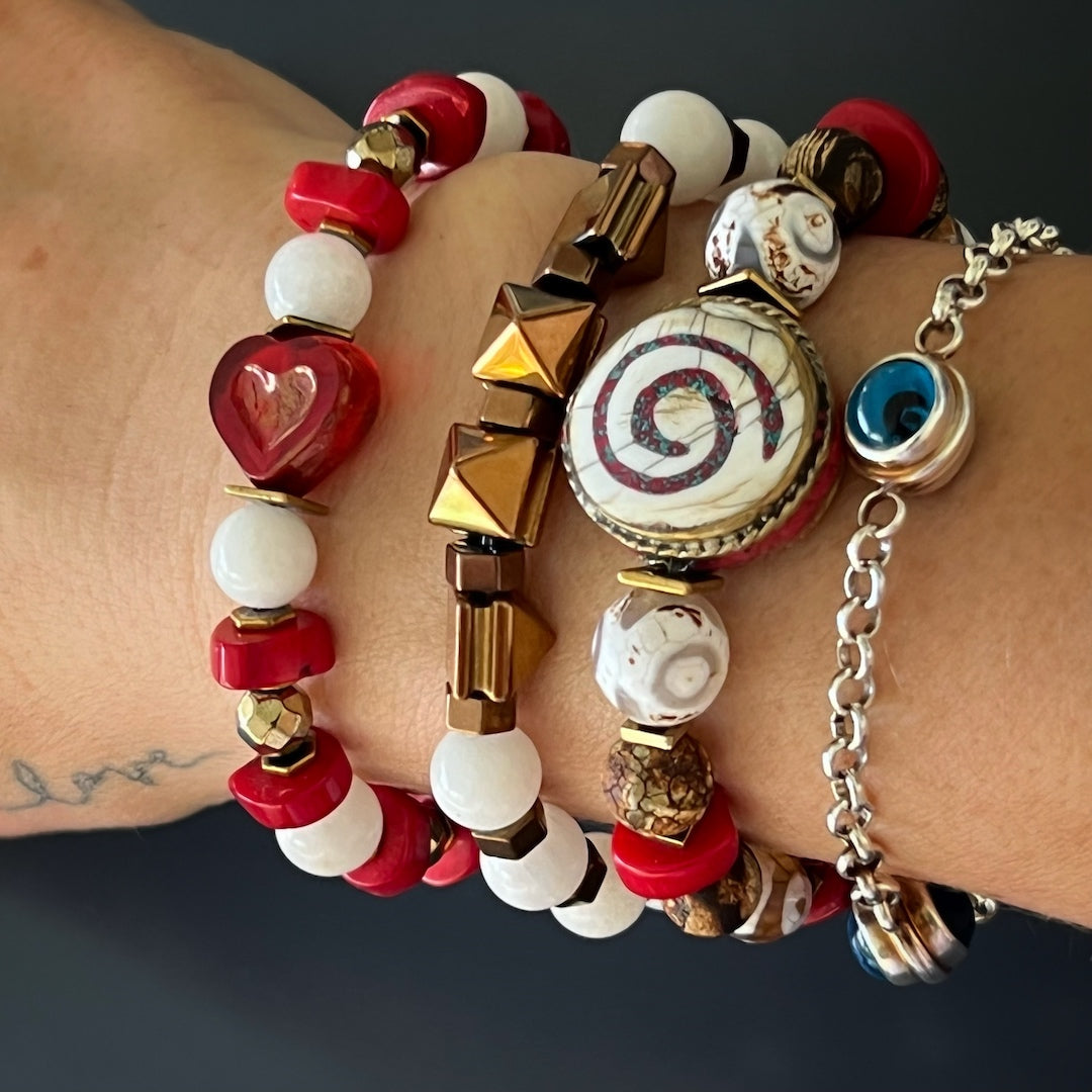 Experience the peaceful energy as the hand model wears the Yoga Spirit Mystic Bracelet, featuring coral stone beads, Nepal meditation beads, and gold color hematite spacers.