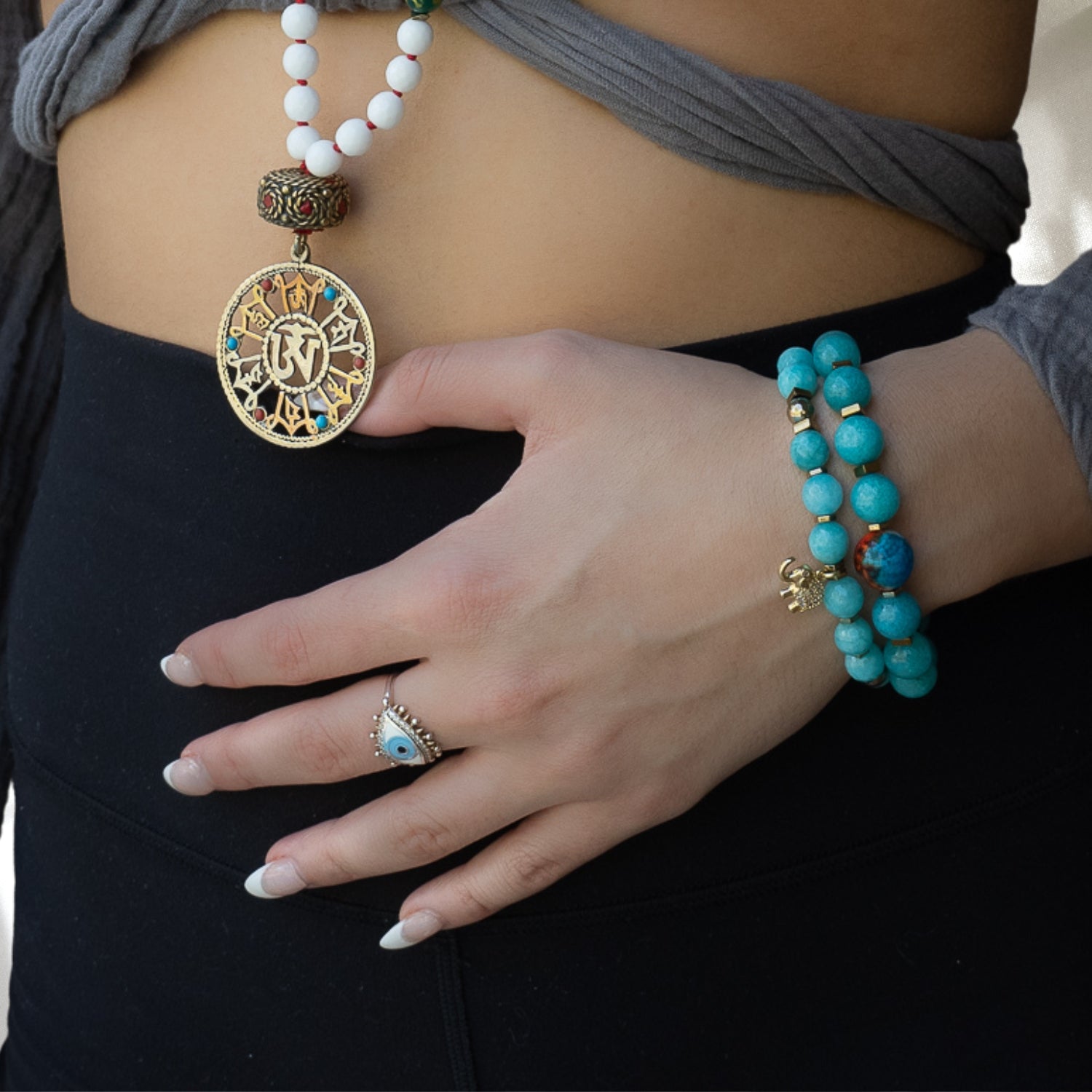 A model wearing the Amazonite Hope Bracelet, featuring a combination of calming pale blue-green amazonite stone beads, gold color hematite stone spacers, African beads and gold hematite stone beads. This unique and one-of-a-kind bracelet is perfect for those looking for a little extra positive energy and hope in their life.