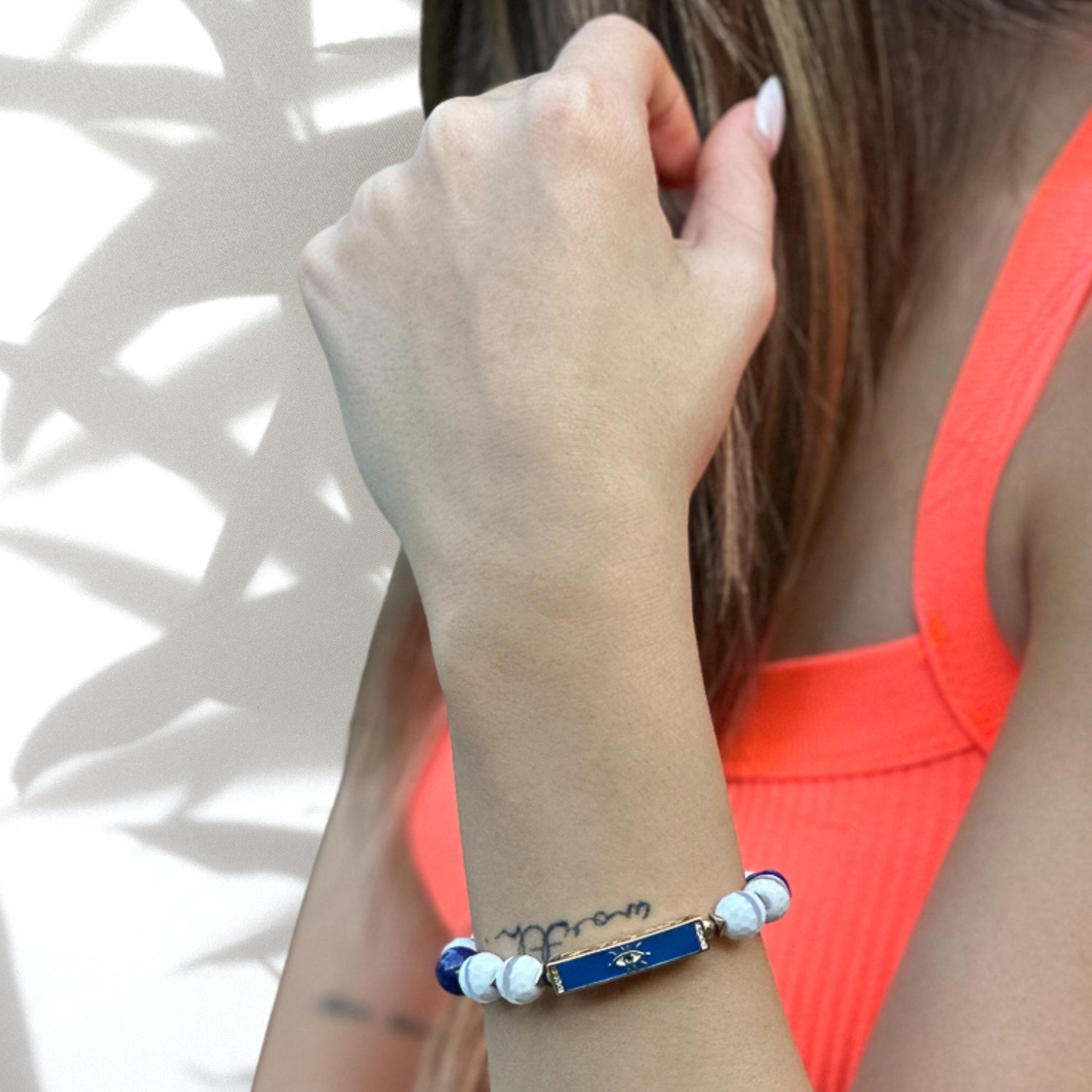 Close-up of Blue Amulet Bracelet with white jade gemstones and evil eye charm, modeled on wrist