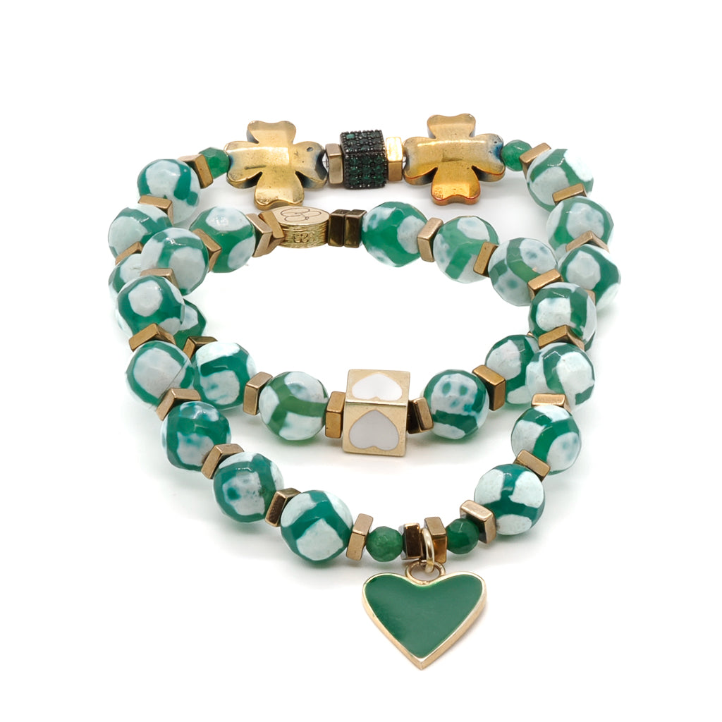 This exquisite bracelet set features Nepal Agate beads, gold hematite clover leaf beads, and a stunning combination of 18K gold-plated green enamel heart charm and white enamel heart bead. The addition of a green Swarovski crystal accent bead adds a touch of sparkle and color to this elegant design.