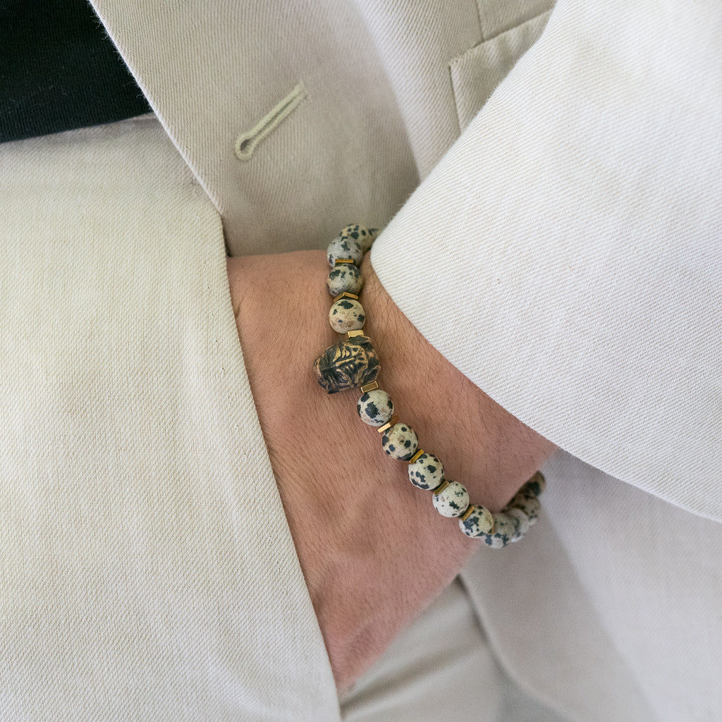 An image with a hand model demonstrating the adjustable feature of the Dalmatian Jasper Dog Bracelet, highlighting its ability to fit comfortably on various wrist sizes.