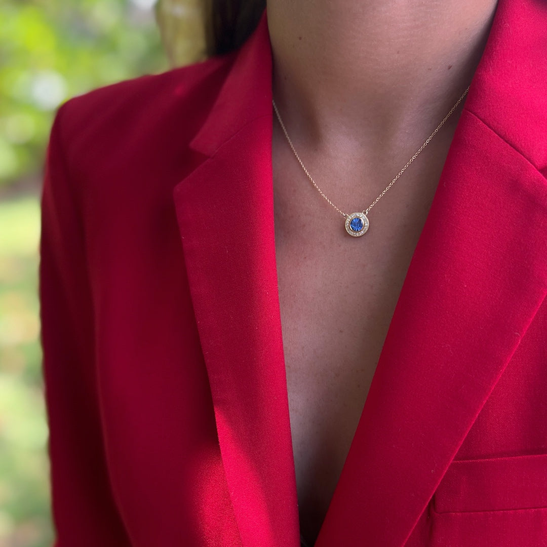 Close-up of a model wearing the Elegant Sapphire Necklace, capturing the attention with the radiant sapphire and the intricate craftsmanship of the gold and diamond details.