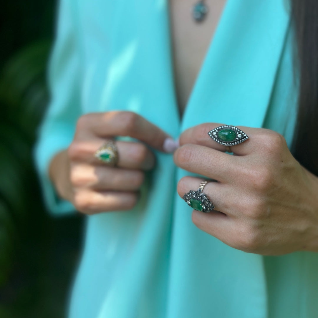 Hand model showcasing the Emerald &amp; Diamond Eye Ring, symbolizing fidelity and love with its stunning emerald centerpiece and dazzling diamonds.