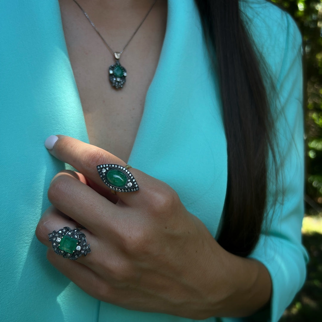 Close-up of a hand model wearing the Emerald & Diamond Eye Ring, capturing the mesmerizing green hue of the emerald and the sparkle of the surrounding diamonds.