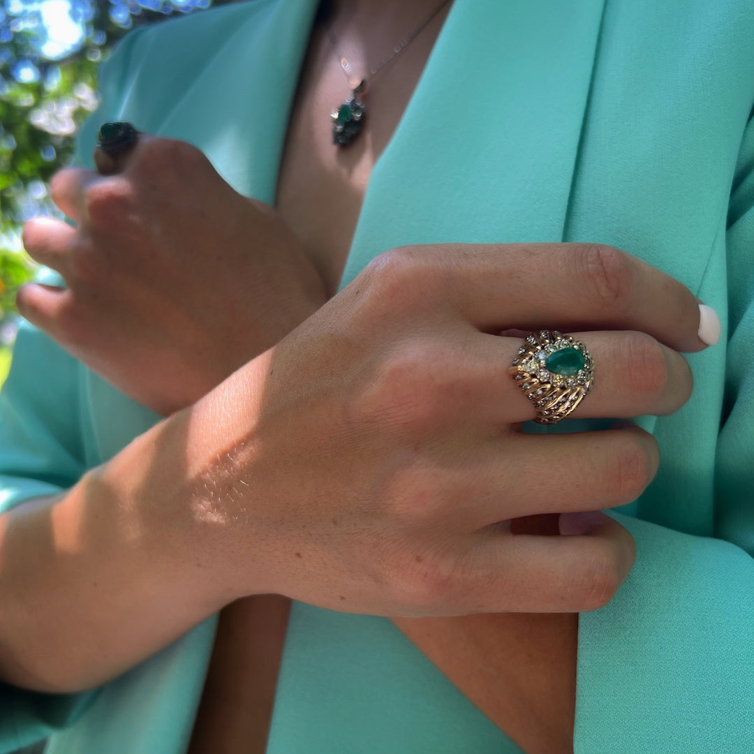 Close-up of a hand model wearing the Emerald &amp; Diamond Eye Ring, showcasing the intricate details of the eye-inspired design and the beauty of the emerald and diamonds.