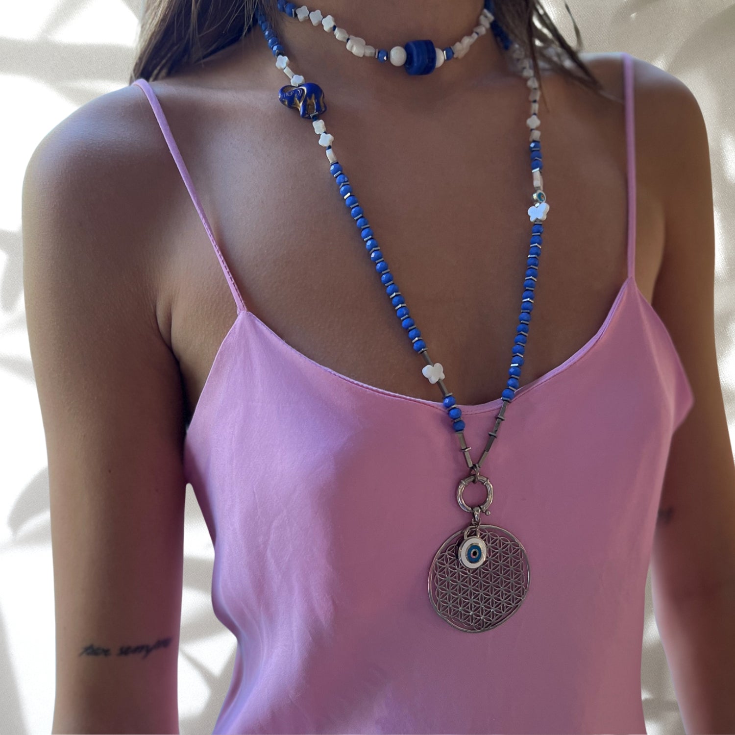 Stylish model wearing Flower of Life Necklace - Meticulously crafted piece with pearl butterfly and flower beads, African elephant charm, and evil eye beads, perfect for showcasing fashion and symbolism