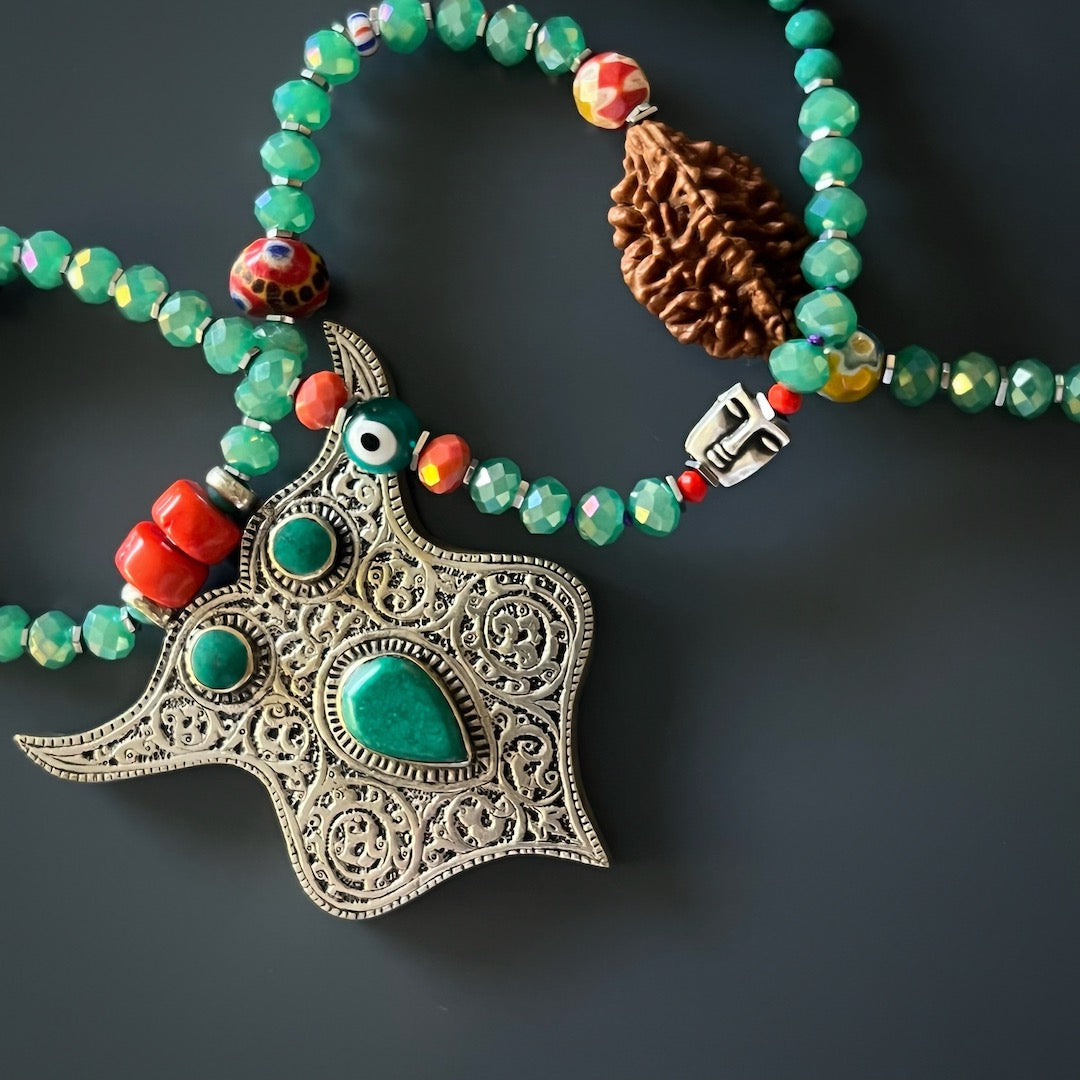 Top-down view of the necklace, highlighting the arrangement of the teal crystal beads, African beads, and Rudraksha mala bead, creating a vibrant and spiritual composition.