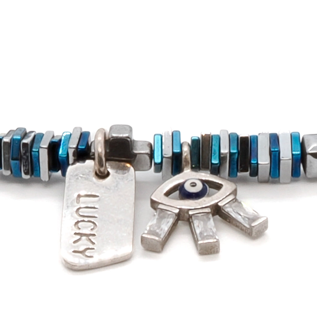 Discover the stylish and symbolic Lucy Evil Eye Bracelet, handmade with blue and silver hematite beads and an exquisite 925 sterling silver evil eye charm adorned with Swarovski crystals.