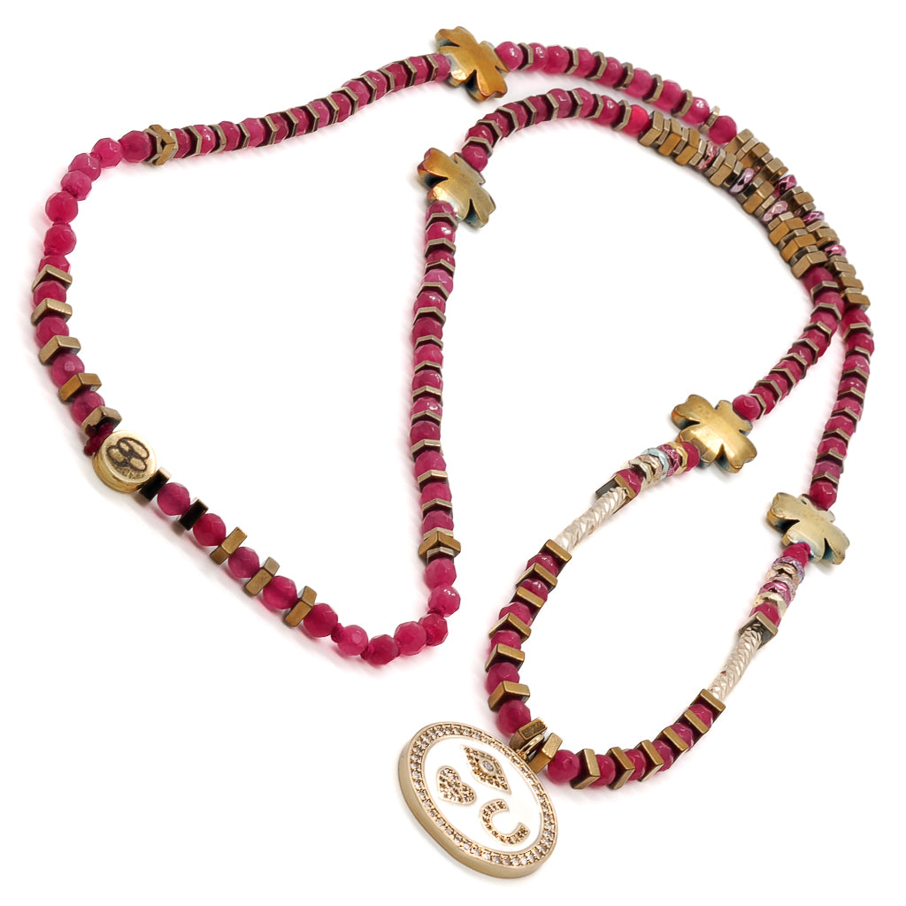 Embrace the significance of the Magic Blessings Pink Necklace, featuring a variety of symbols including an evil eye, horseshoe, heart pendant, and lucky flowers, beautifully crafted with hot pink faceted jade stone beads and gold-colored hematite spacers.