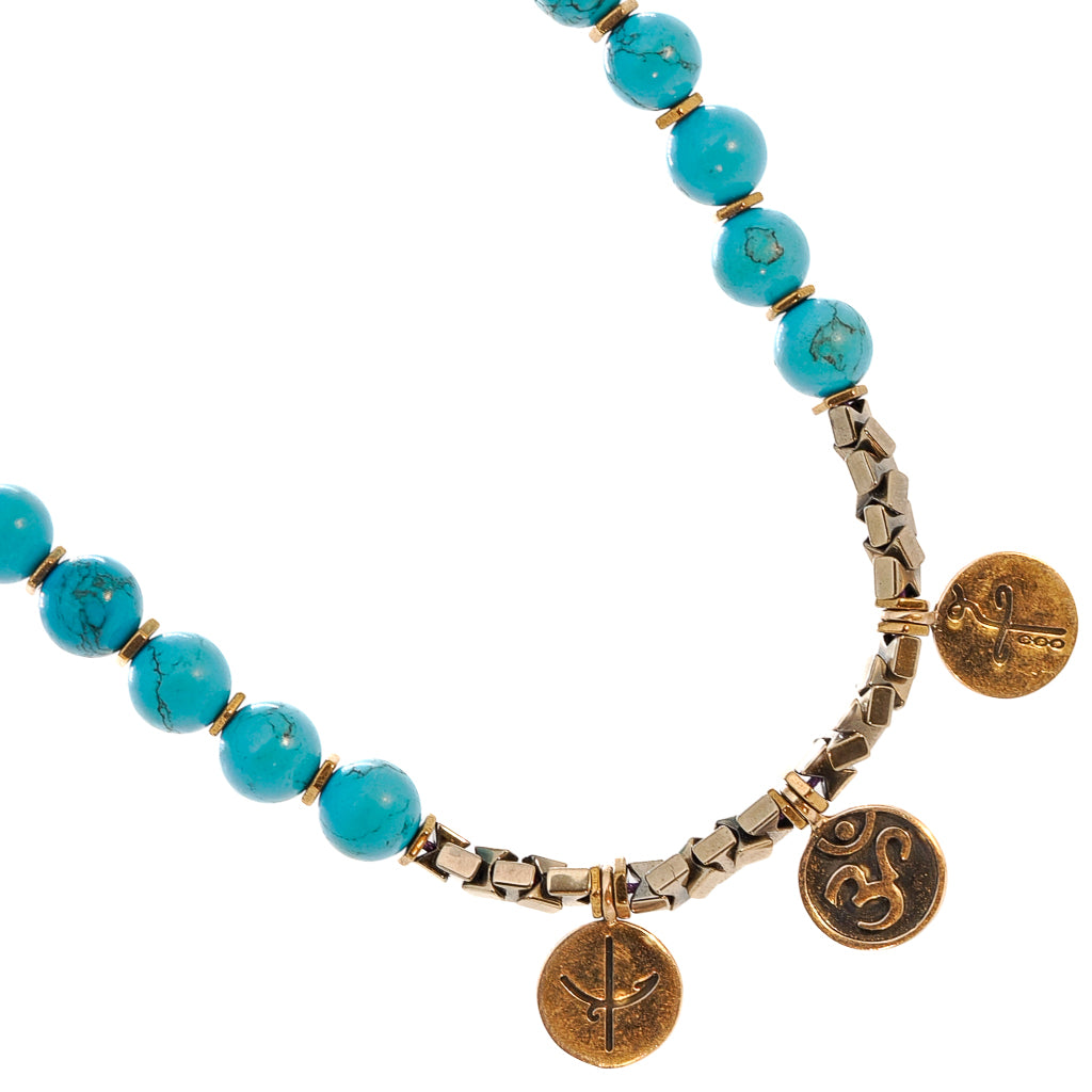 Vibrant turquoise stone beads and symbolic charms of the Mystic Meditation Necklace.