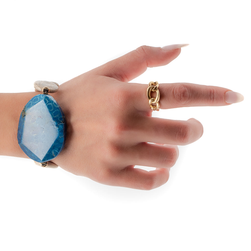 The model embraces the sophistication of the New World Bracelet, showcasing its unique combination of blue agate gemstone beads and gold hematite spacers.