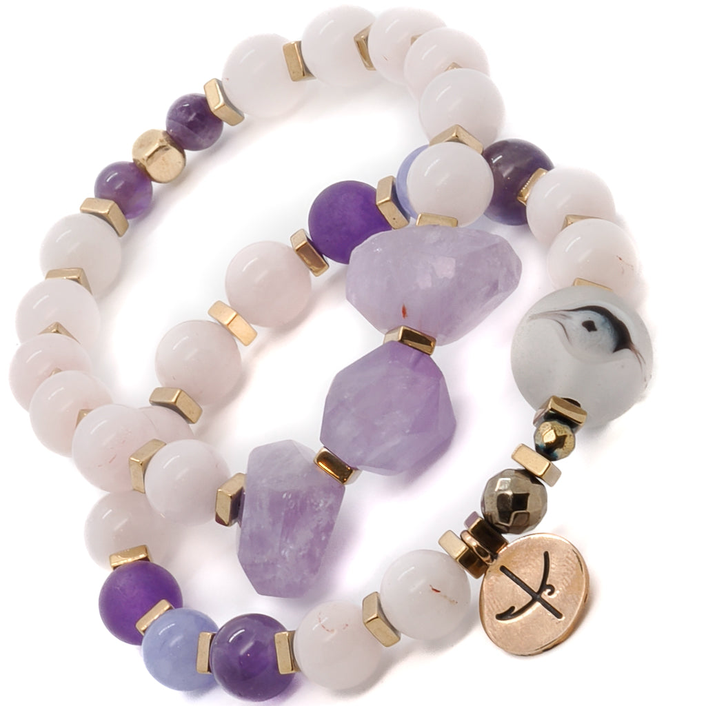 Discover the beauty and tranquility of the Peaceful Mind Bracelet Set, adorned with rose quartz and amethyst beads, a glass evil eye bead, and a bronze Dream mantra charm.