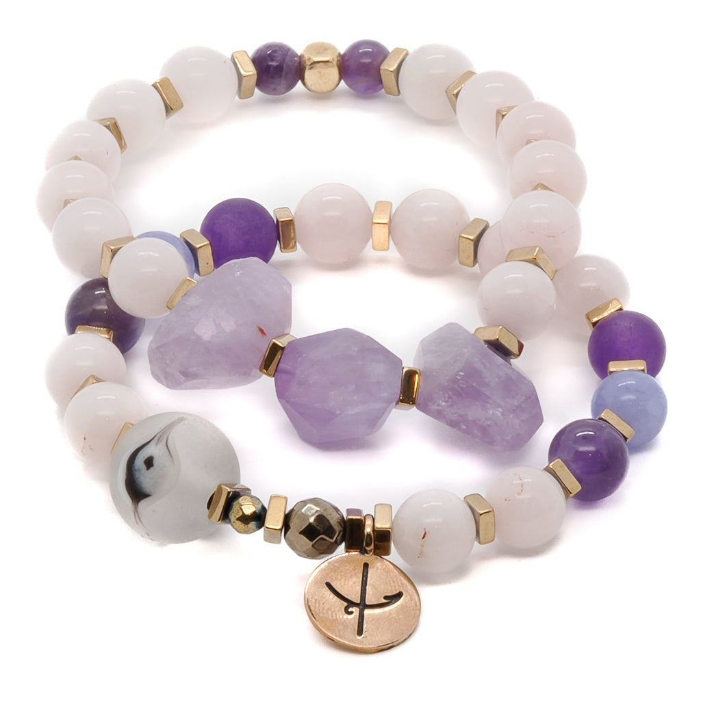 The Peaceful Mind Bracelet Set promotes calmness and spiritual awareness, featuring rose quartz and amethyst beads, a glass evil eye bead, and a bronze Dream mantra charm.