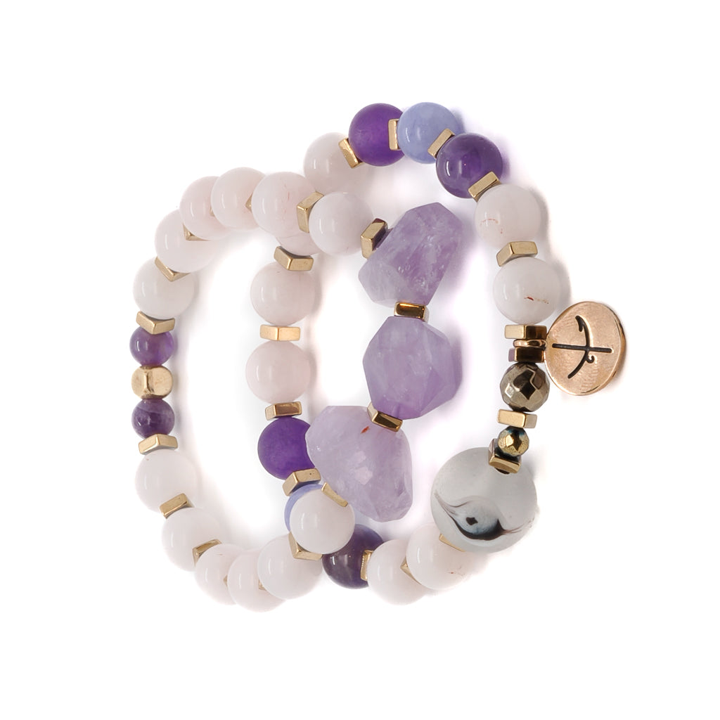 Find inner tranquility with the Peaceful Mind Bracelet Set, featuring rose quartz and amethyst beads, a glass evil eye bead, and a bronze Dream mantra charm.